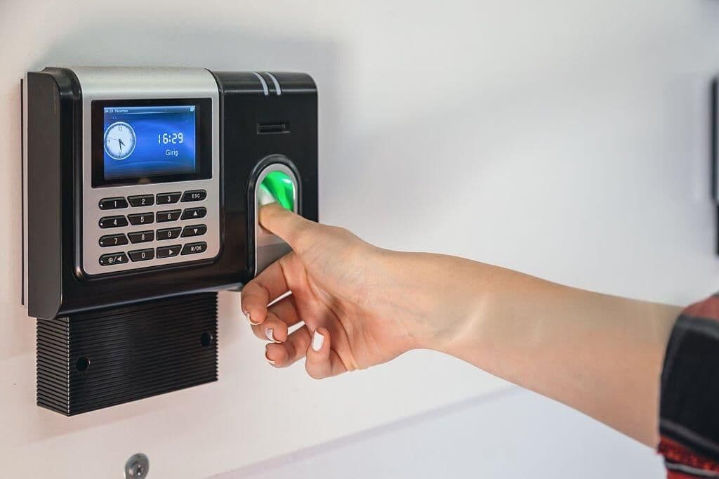 Hand scanning a fingerprint on a digital attendance check-in device