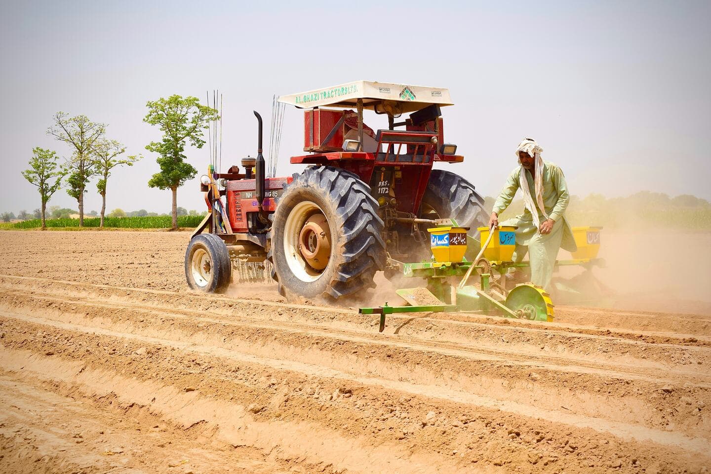 Tractor pulling seeding and input equipment across a field, representing harvest-season logistics planning