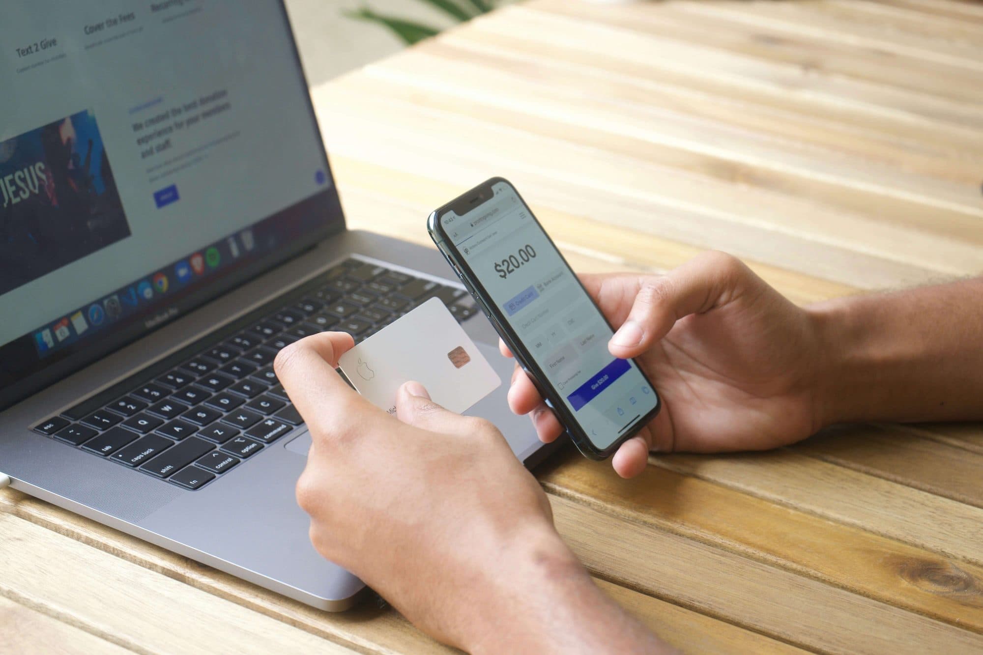 Completing a mobile card payment next to a laptop, representing a fintech payments flow