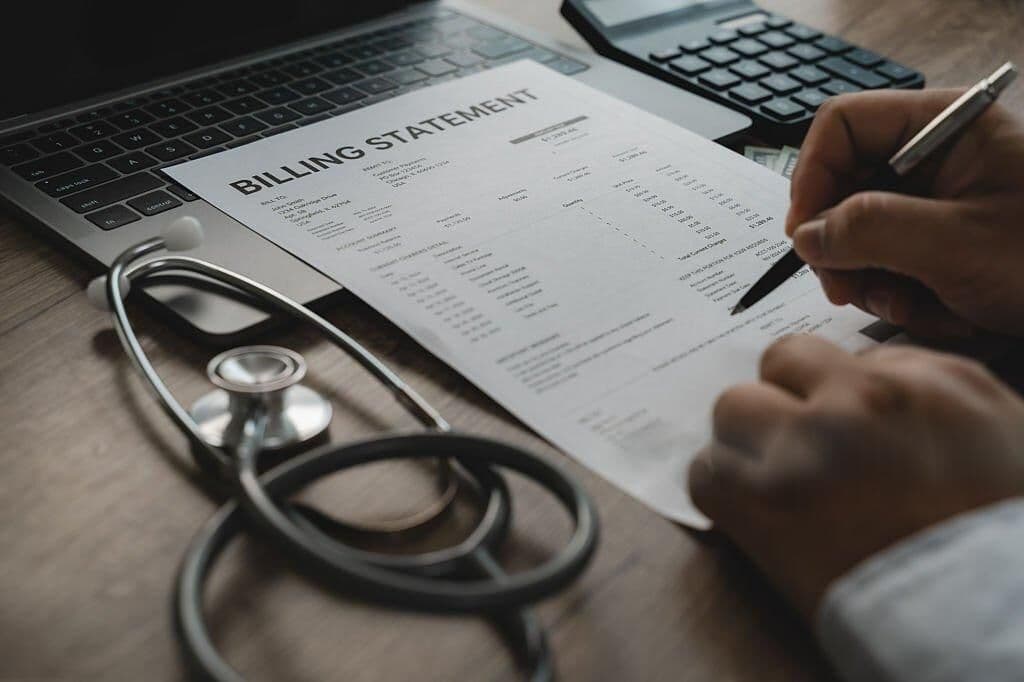 Close-up of a medical billing statement next to a stethoscope and calculator on a desk